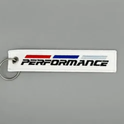 BMW nyckelring i mjukt vitt tyg med M Performance-logotyp – perfekt kombination av komfort och sportig design för BMW-entusiasten.